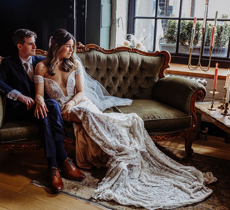 Bride and groom sit relaxed together on a sofa 