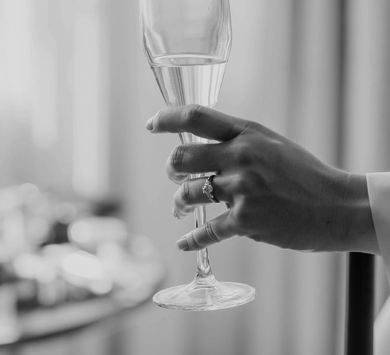 Bride has a glass of champagne showing her diamond engagement ring 