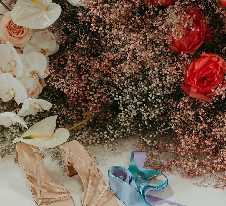 Beige wedding shoes with wedding stationery with colourful letters and gold jewellery with coloured gypsophila 