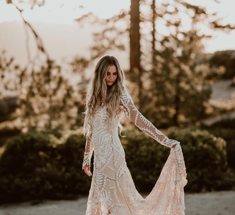 Bride in a long sleeve lace wedding dress with a boho style pattern