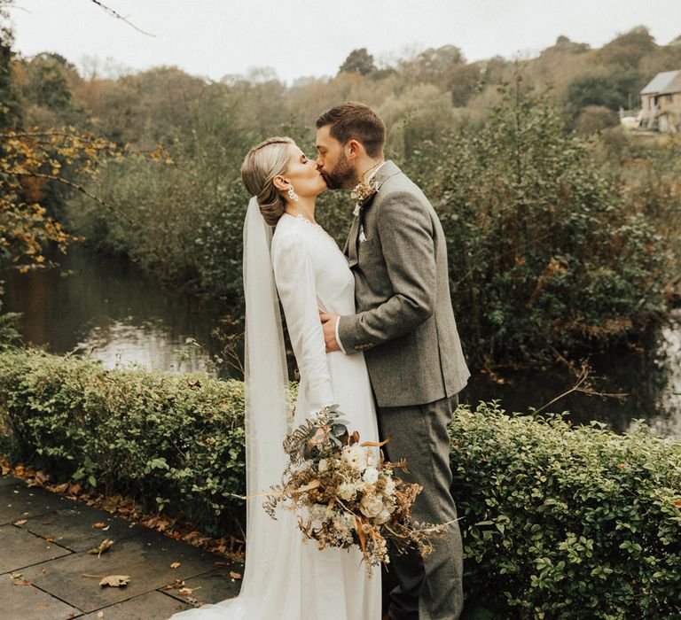 Bride in Reformation dress kisses her groom outdoors 