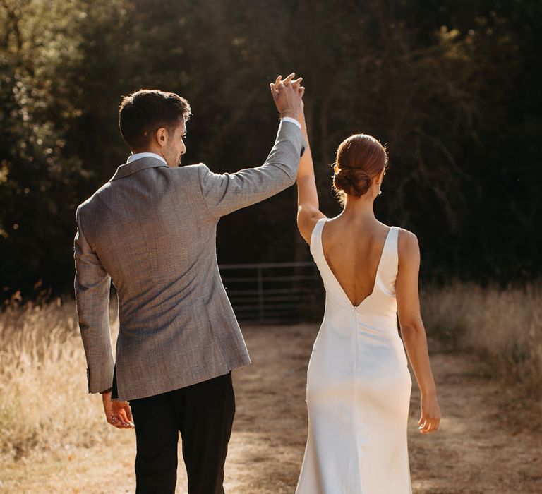 Bride wears fitted silk wedding dress with V-shaped back 