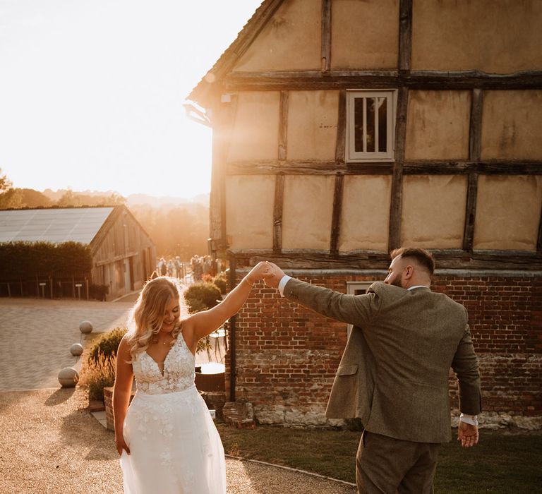 The groom spins the bride around during the sunset 