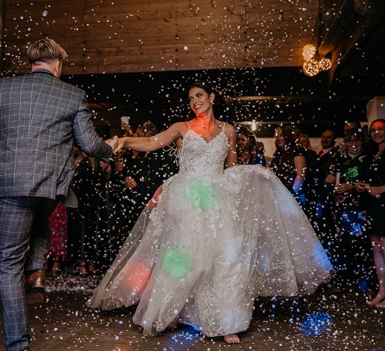 Bride and groom have their first dance together as confetti explodes around them and colourful disco lights shine 