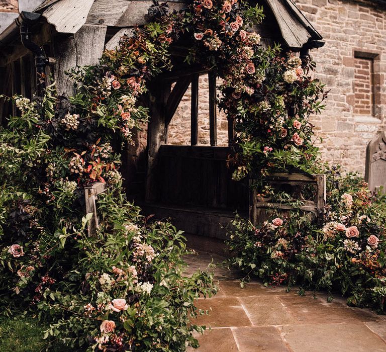 Church wedding with extravagant autumnal flower arch decorating the entrance 