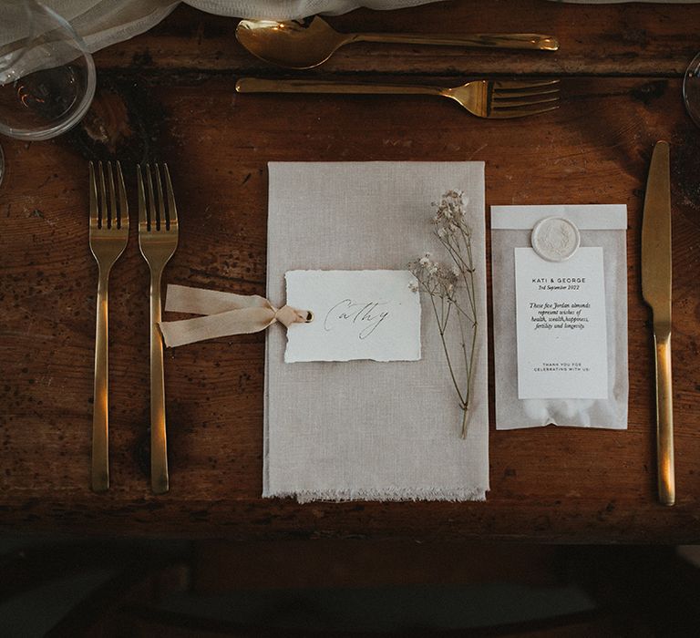 Neutral fabric napkins with gold cutlery on wooden banquet tables 