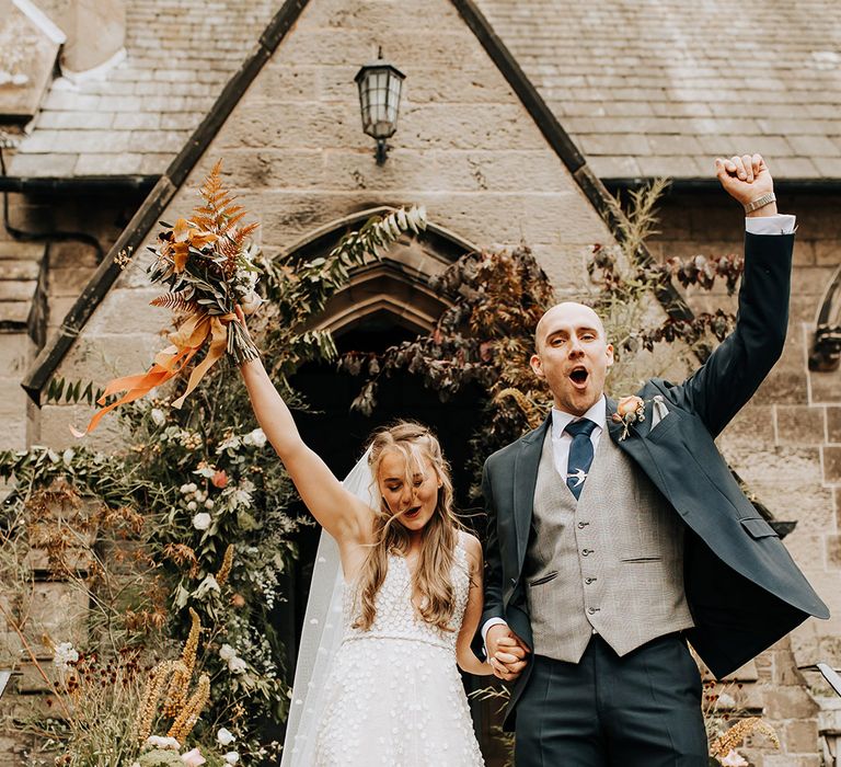 The bride and groom celebrate on the entrance stairs of the church after being announced as a married couple 