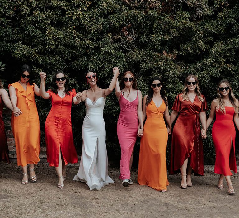 Bridal party in different pink, orange, rust and red bridesmaid dresses 