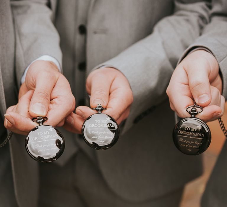 The groomsmen and groom have matching black personalised pocket watches for the wedding day 