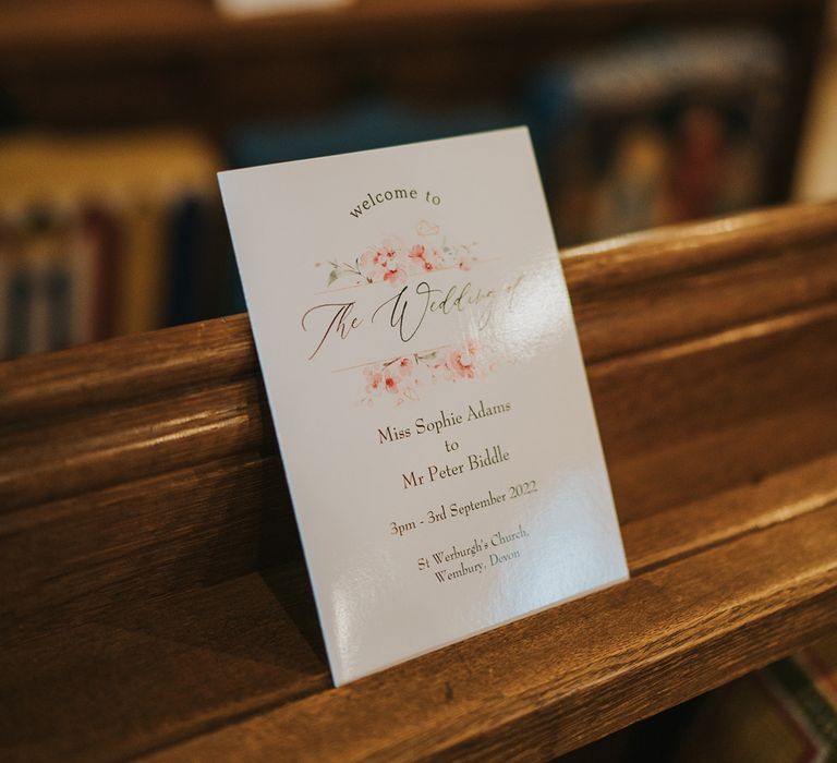 Pale pink and white floral order of service booklet in the church for the ceremony 