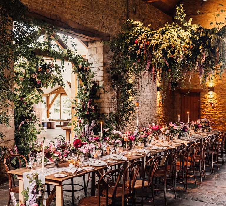 One long banquet table for an intimate wedding decorated with pink and purple flowers and candles for cosy romantic wedding 