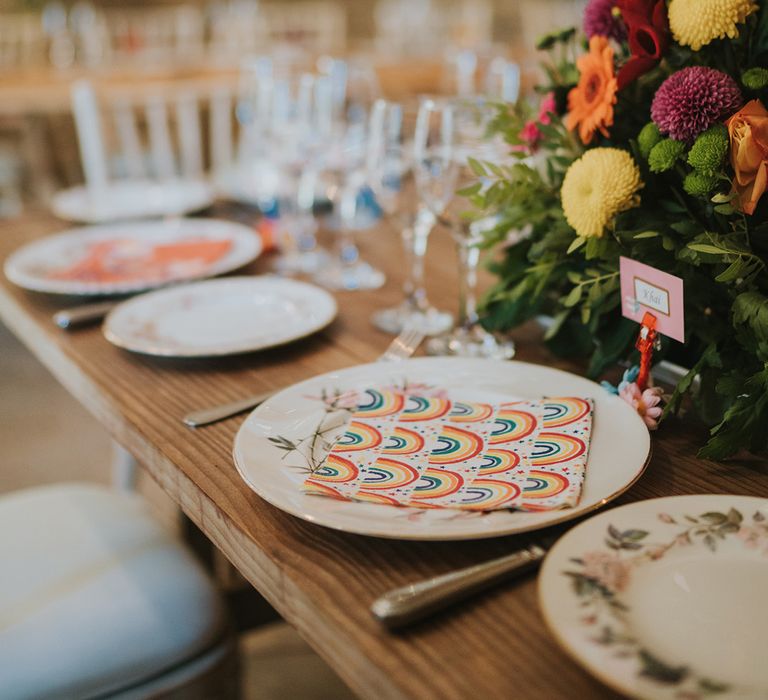 place setting with patterned tableware and rainbow paper napkin 