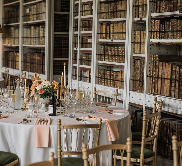 Library wedding breakfast with autumnal wedding tablescape with taper candles, small table centrepieces and wedding stationery 