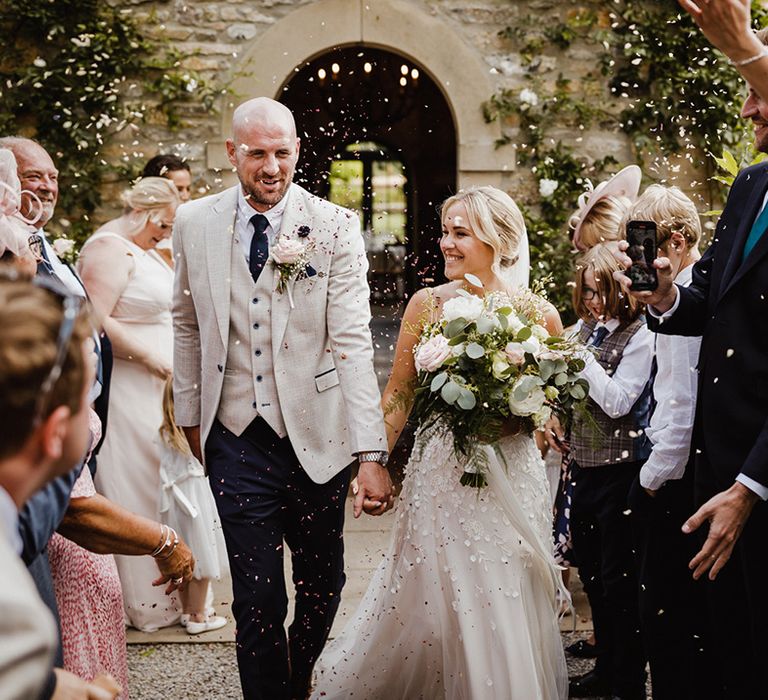 The bride and groom walk back down the aisle as a married couple after their outdoor summer wedding 