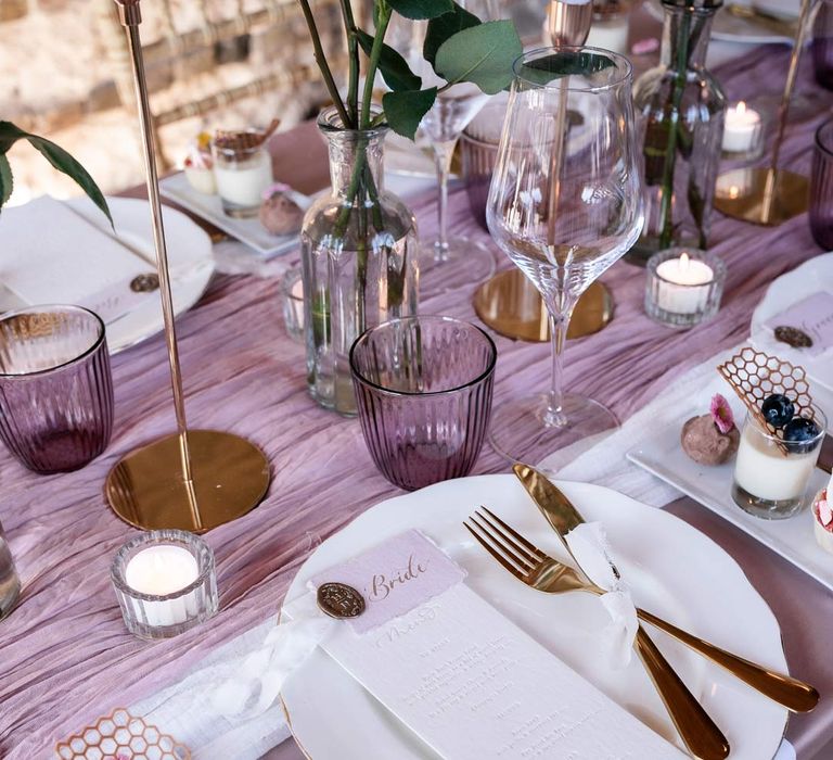 Modern wedding tablescape with lavender tablecloth, lilac tulle table runner, blush garden rose centrepieces, tea light candles and a trio of mini desserts 