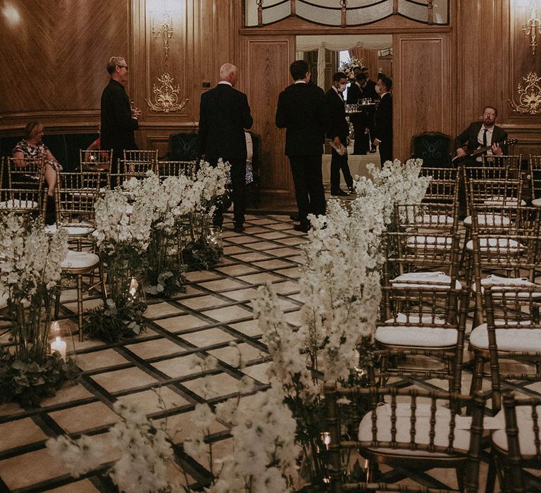 The aisle at the ceremony room at Claridge's hotel in London is decorated with white flowers for the aisle decorations 