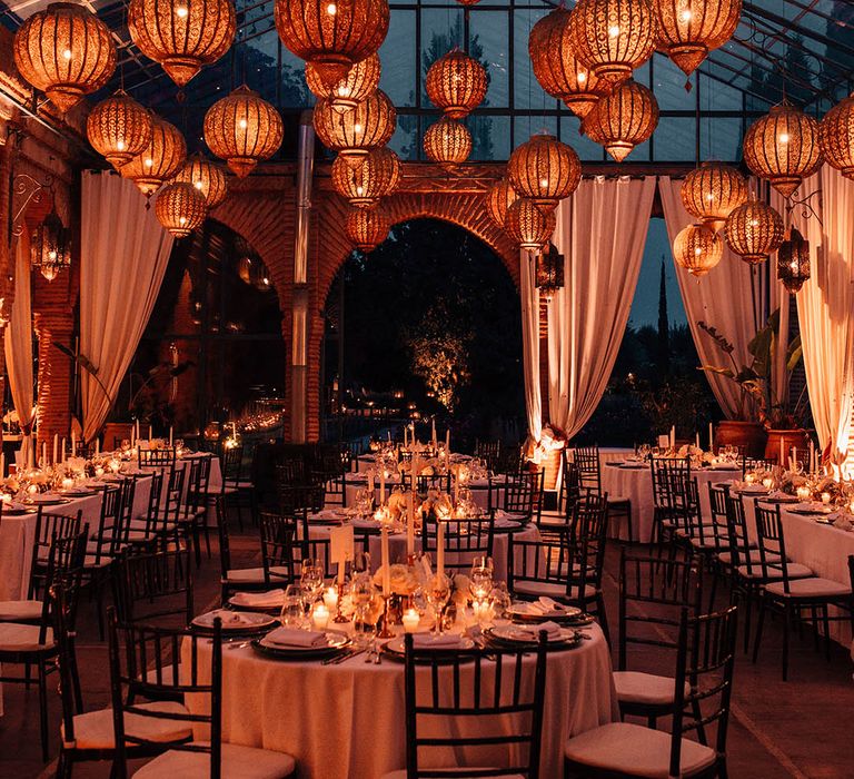 Beldi Country Club glass house wedding venue with golden lanterns and candlelight with white wedding drapery 