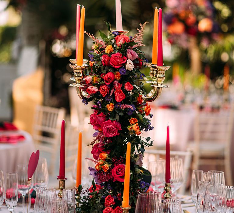 Tall decorative floral table centrepiece with colourful taper candles for glasshouse wedding 