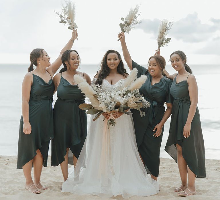 Bridesmaid dresses in forest green dresses in mismatched styles for beach wedding with dry pampas grass bouquets 