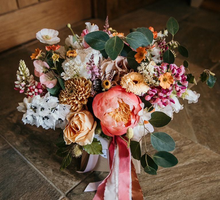 Peony wedding bouquet with dahlias and poppies tied with ribbons 