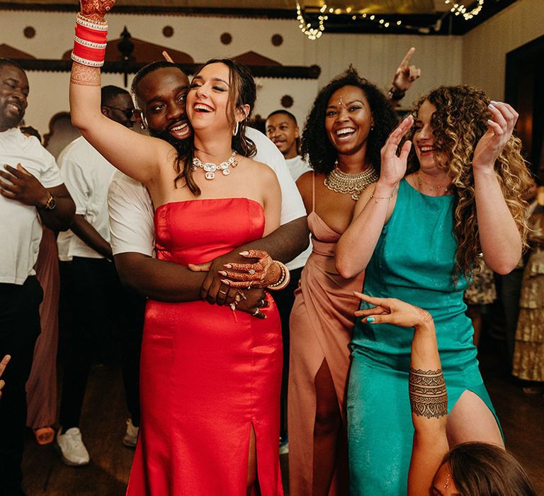 Bride in red strapless wedding reception dress dancing with wedding guests at the wedding reception 