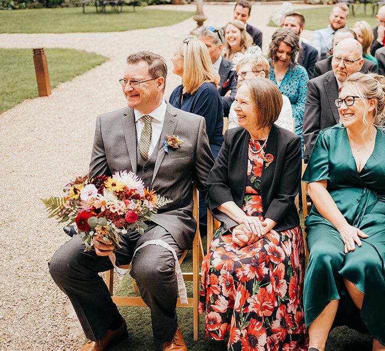 Smiling wedding guests seated for the outdoor wedding ceremony 