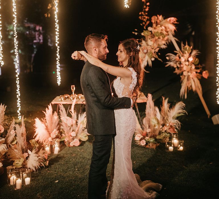 bride and groom outdoor first dance at tenuta il cigno wedding with hanging fairy light decor 