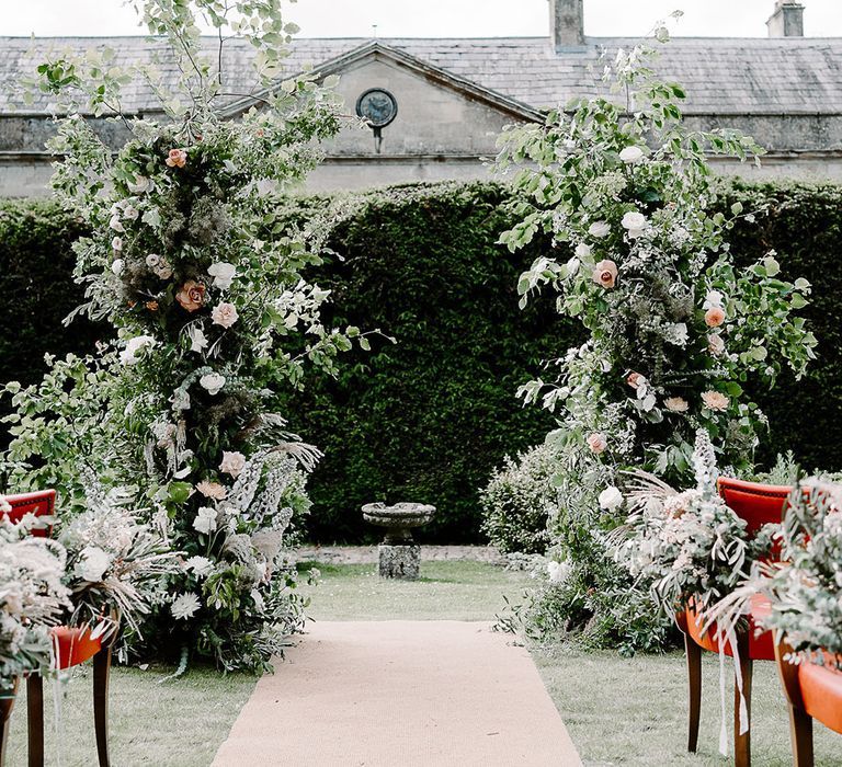 Flower columns decorating altar at Babington House outdoor wedding ceremony 