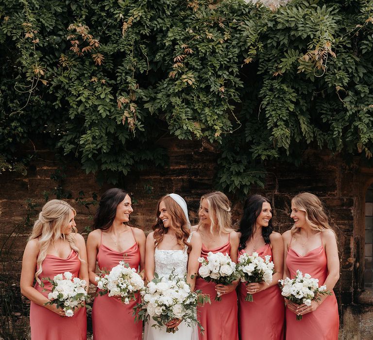 Bridal party wearing coral pink bridesmaid dresses with white Loeffler Randall bow shoes 