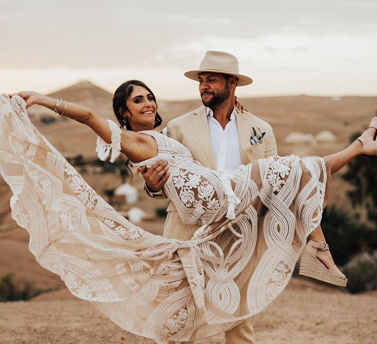 The groom spins the bride around in her boho lace wedding dress from Rue De Seine 