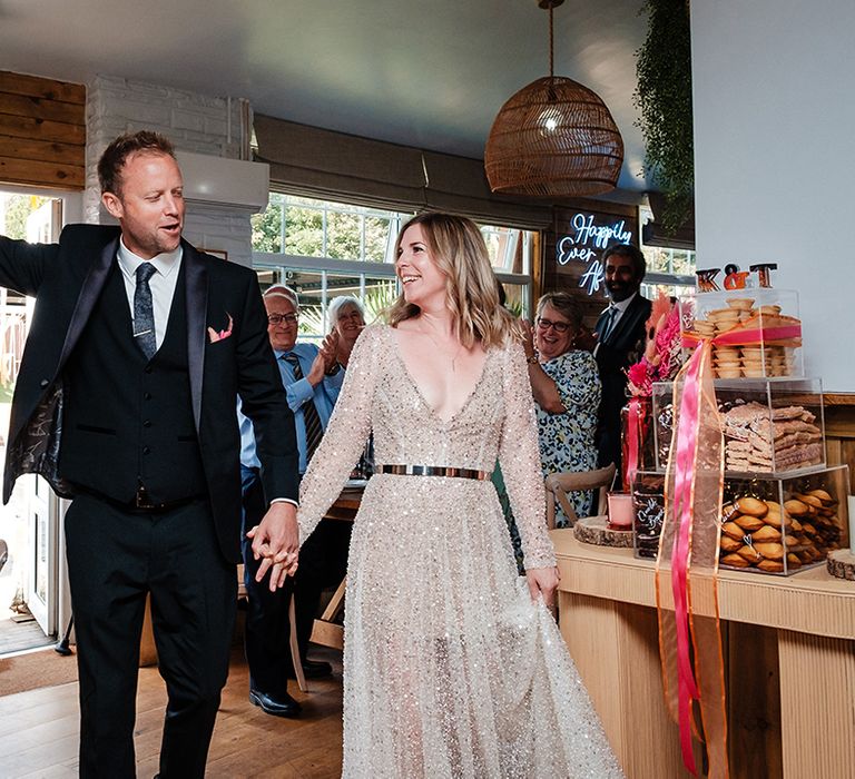 The bride and groom walk into their wedding reception together 