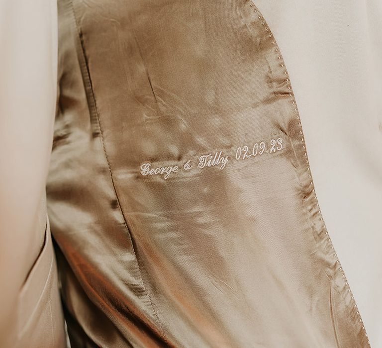 Embroidered detail on the groom's suit lining with the bride and groom's names and wedding date 