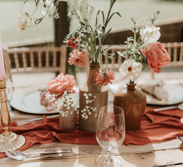 Burnt orange wedding table decorations with roses, gypsophila sitting on table runner 