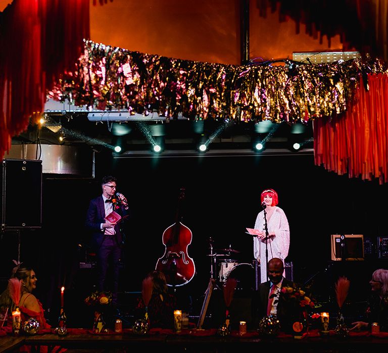 Bride and groom read out wedding speeches on stage for music themed wedding