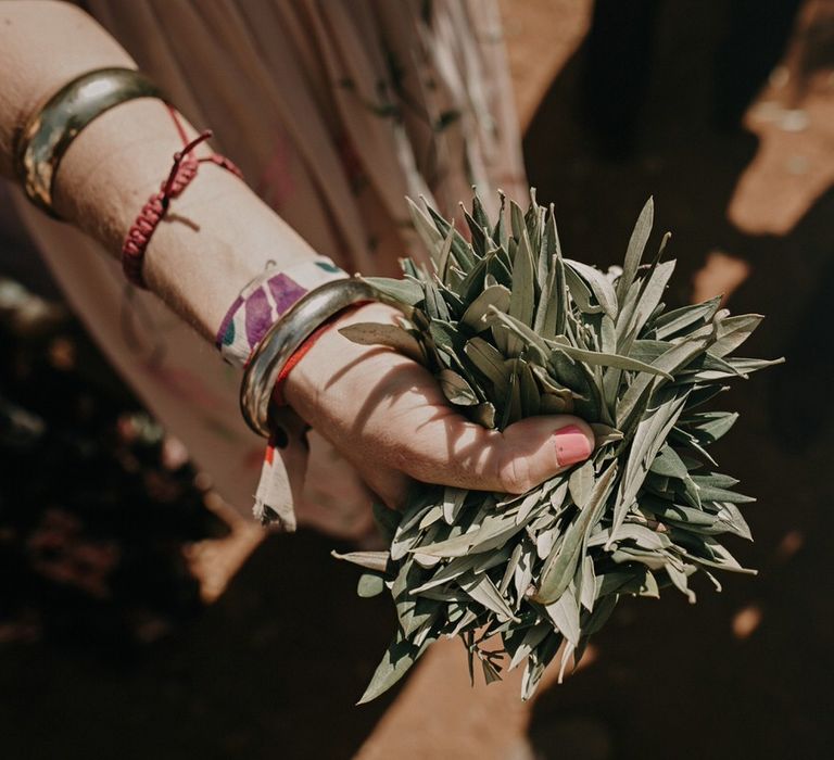 Guests hold olive leaves to throw as wedding confetti