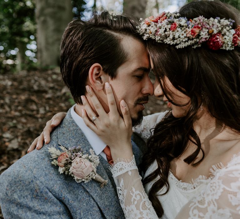 Close up portrait of bride and groom in woodland. Bride wears dried flower crown.