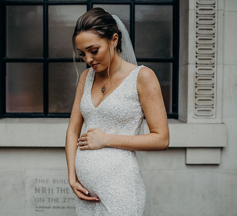 Pregnant bride holding her bump at intimate Town Hall wedding 