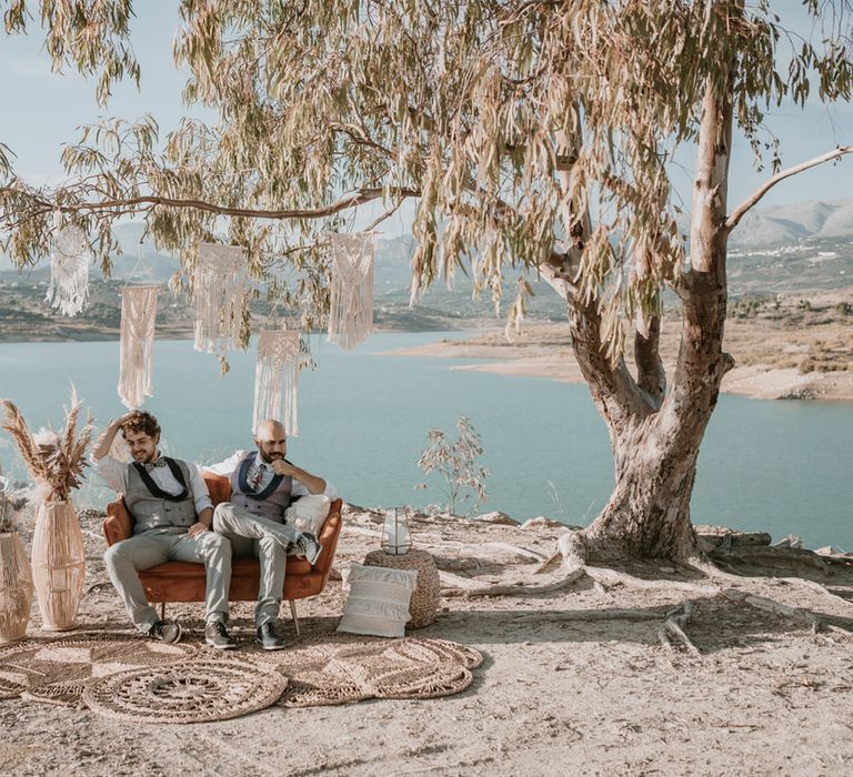 Macrame decorations hang from the trees as the couple relax on velvet furniture