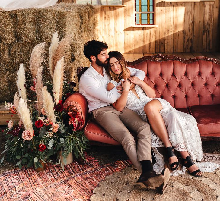 Bride & groom embrace on chic pink sofa outdoors