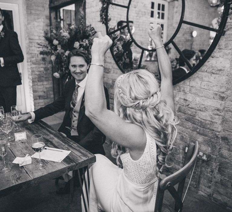 Bride with curly wedding hairstyle cheers at smiling groom at Iscoyd Park wedding reception dinner