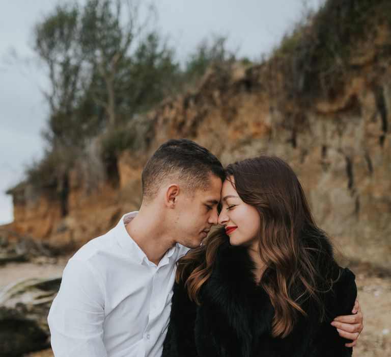 Bride and groom-to-be sitting on a log on the beach during their engagement photo shoot