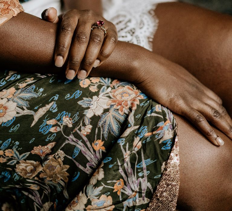 Black bride in a patterned getting ready robe showing her ruby engagement ring 