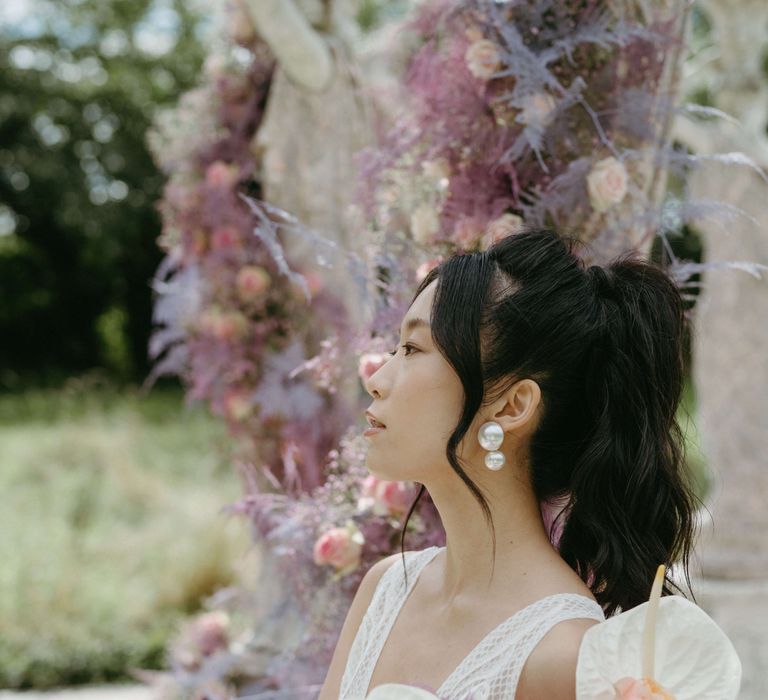 Bride wears her hair in high ponytail and wears large pearl drop earrings