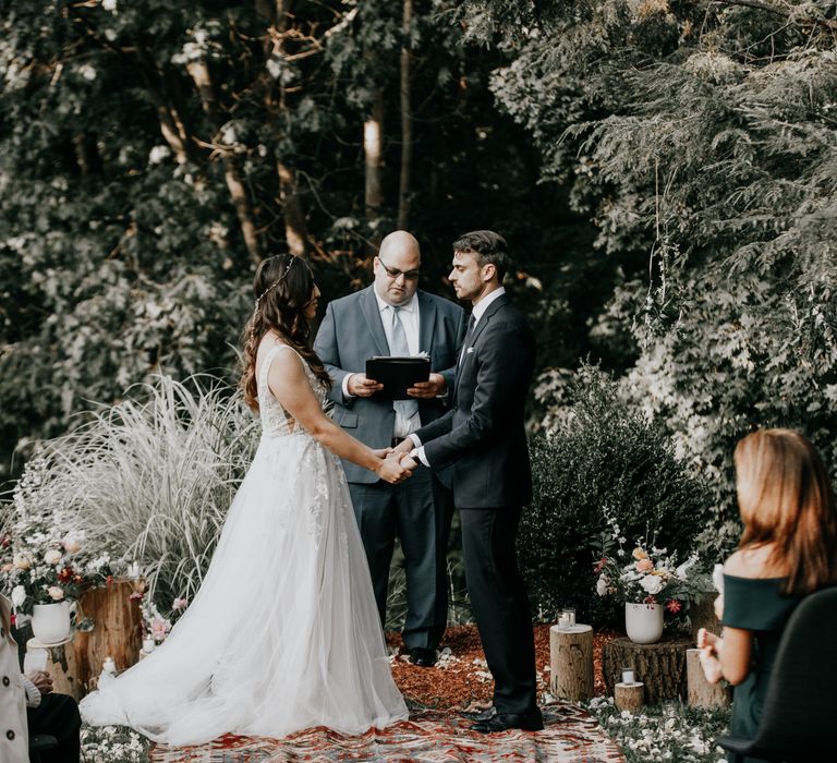 Bride & groom hold hands during wedding ceremony outdoors