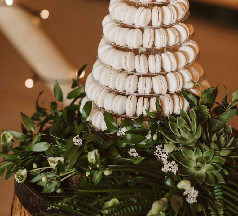 White macaroon tower with green foliage to the bottom