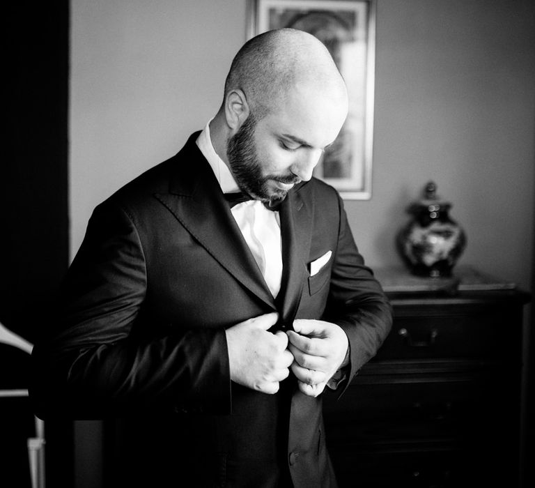 Groom buttoning his wedding suit blazer by Sartoria Rossi