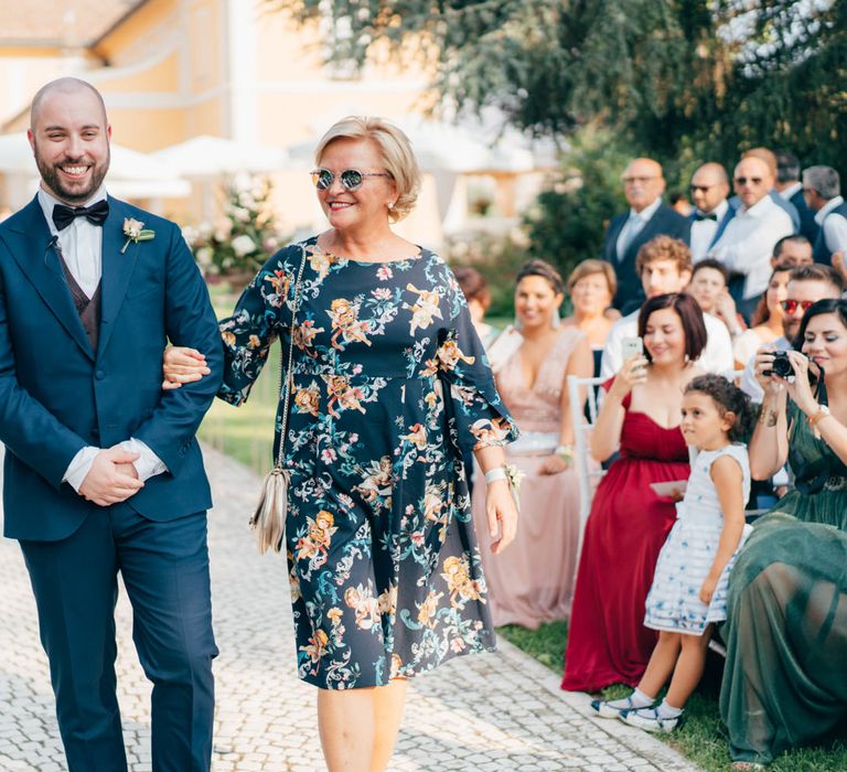 The groom and his mother walking down the aisle arm in arm