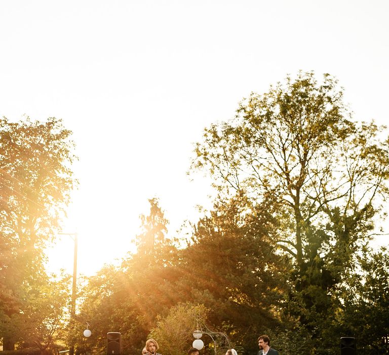 Bride & groom marry outdoors whilst the light streams through the trees