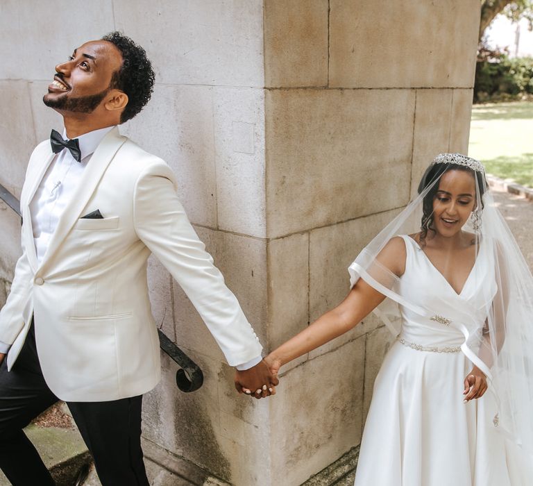 Bride and groom holding hands around a corner before the wedding ceremony 