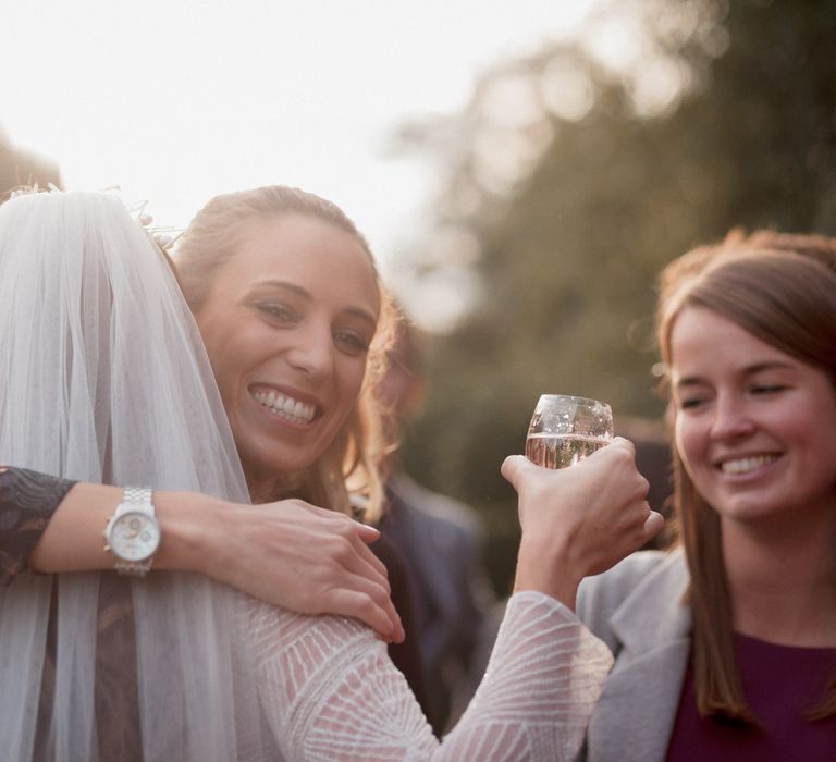 Wedding guest hugging bride wearing veil 